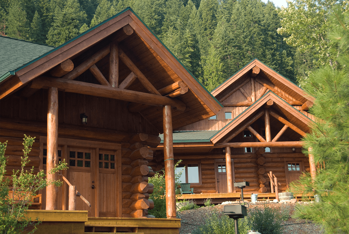 two log cabins surrounded by green trees at the River Dance Lodge