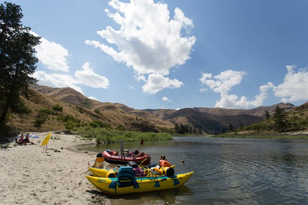 a bright yellow small catamaran and red raft dock in sand at a beach along the Salmon River in North Central Idaho