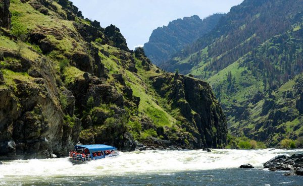 a blue jet boat, surrounded by whitewater rapids, makes its way through the Snake River, in Hells Canyon